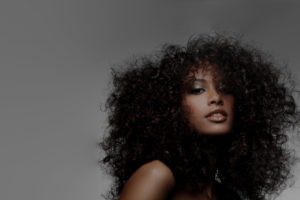 Woman with voluminous curly hair, confident expression.